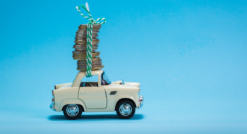 The image displays a car carrying coins. This represents the increase in HMRC Recommended rate to 55ppm